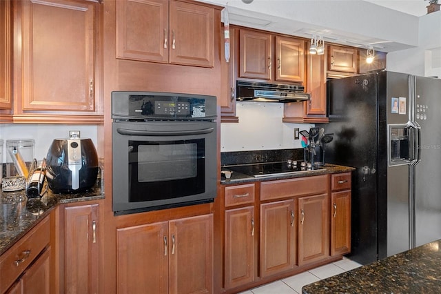 kitchen with dark stone countertops, black appliances, light tile patterned floors, and ventilation hood