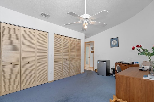 office with ceiling fan, a textured ceiling, lofted ceiling, and dark colored carpet