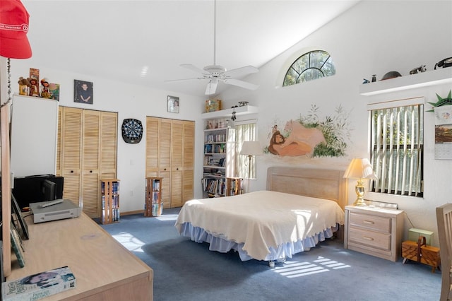 carpeted bedroom with two closets, high vaulted ceiling, and ceiling fan