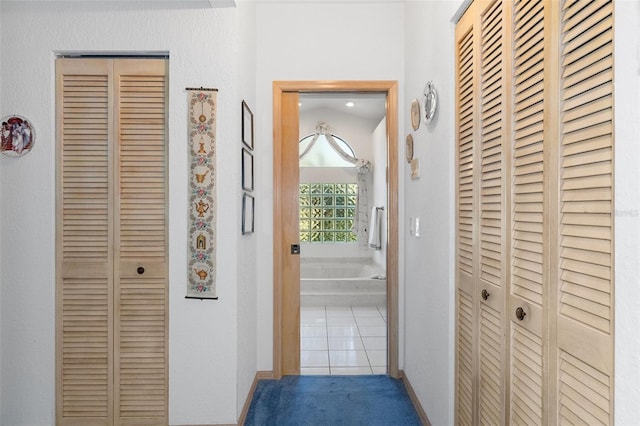 hallway with tile patterned floors and lofted ceiling