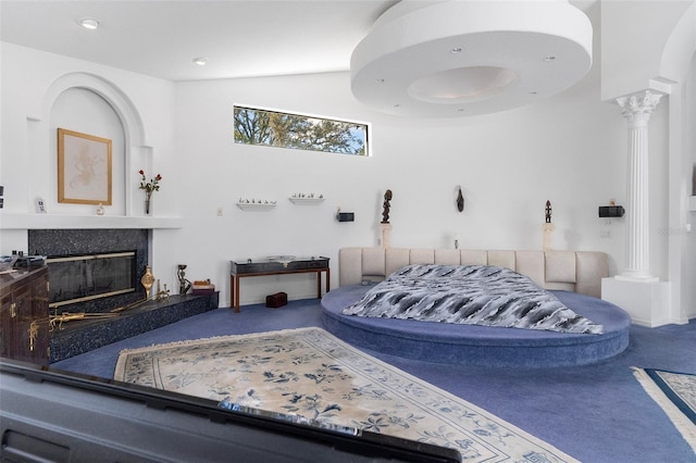 carpeted bedroom featuring a premium fireplace, lofted ceiling, and decorative columns