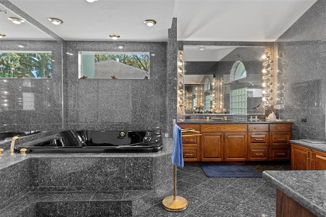 bathroom with vanity, tile walls, and tiled bath