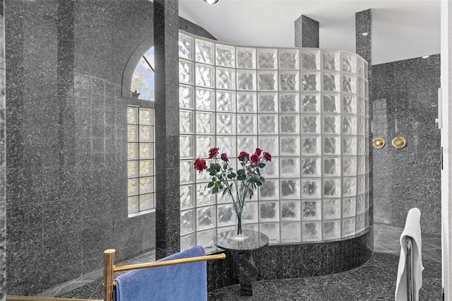 bathroom featuring tile walls, a tile shower, and a textured ceiling