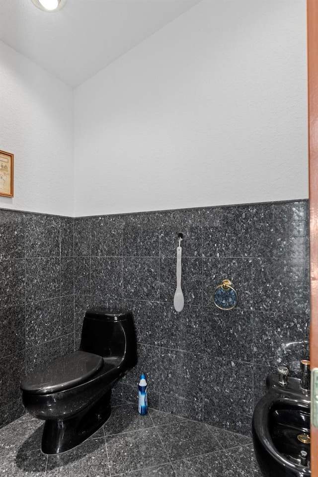 bathroom featuring tile walls and toilet