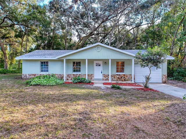 ranch-style home with covered porch, a front yard, and a garage