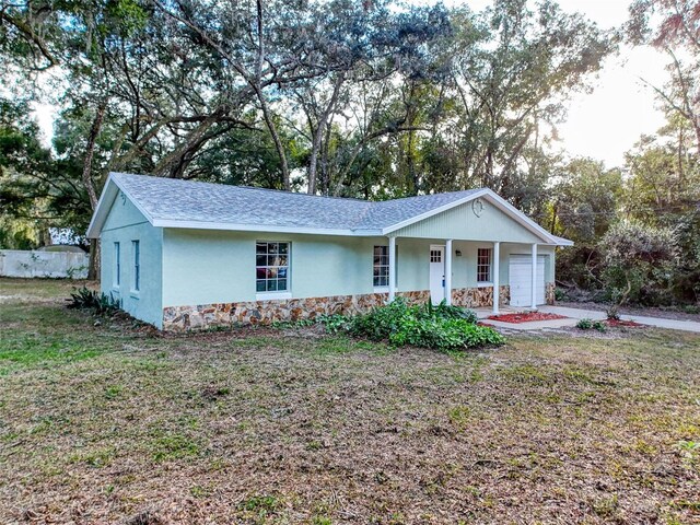 ranch-style home with a porch, a front lawn, and a garage