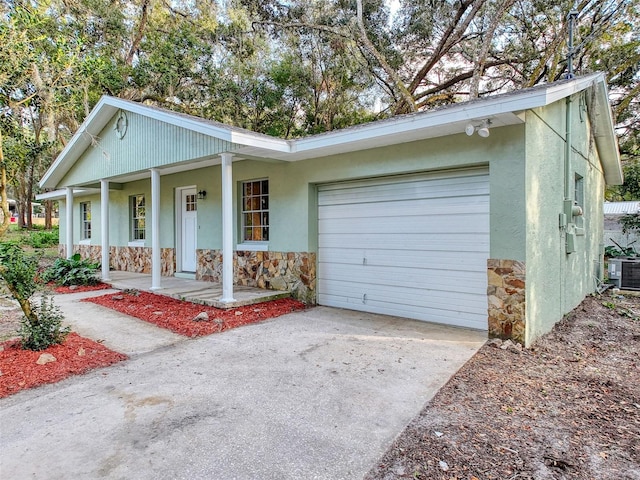 ranch-style house featuring a garage, central AC unit, and a porch