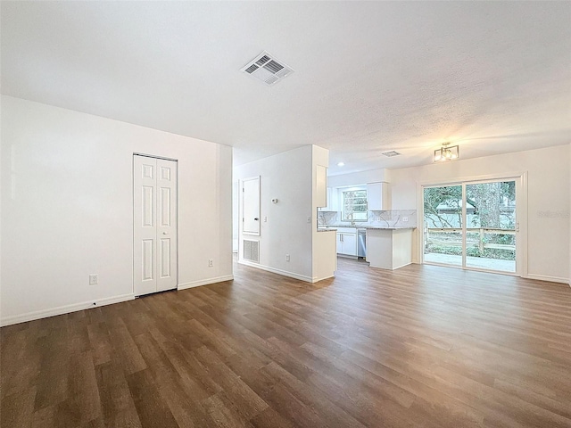 unfurnished living room with sink, wood-type flooring, and a textured ceiling