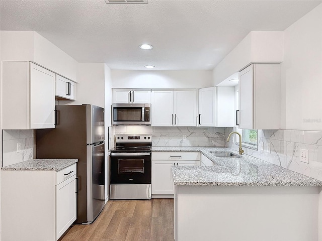 kitchen featuring light stone counters, white cabinetry, light hardwood / wood-style flooring, sink, and stainless steel appliances