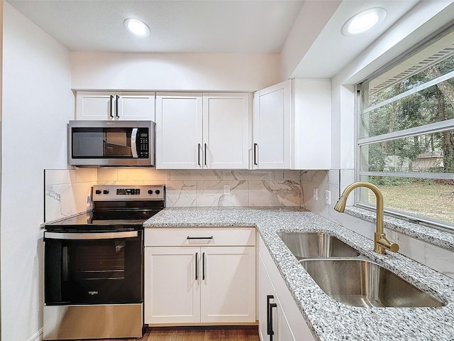 kitchen featuring appliances with stainless steel finishes, white cabinets, sink, and backsplash