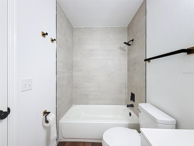 full bathroom with vanity, tiled shower / bath, a textured ceiling, and toilet