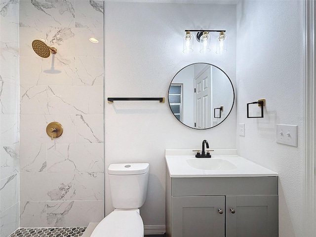 bathroom featuring vanity, toilet, and tiled shower