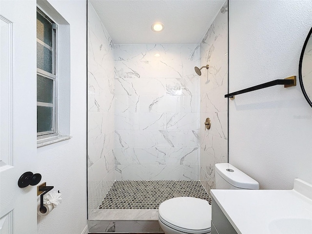 bathroom featuring toilet, a textured ceiling, vanity, and a tile shower