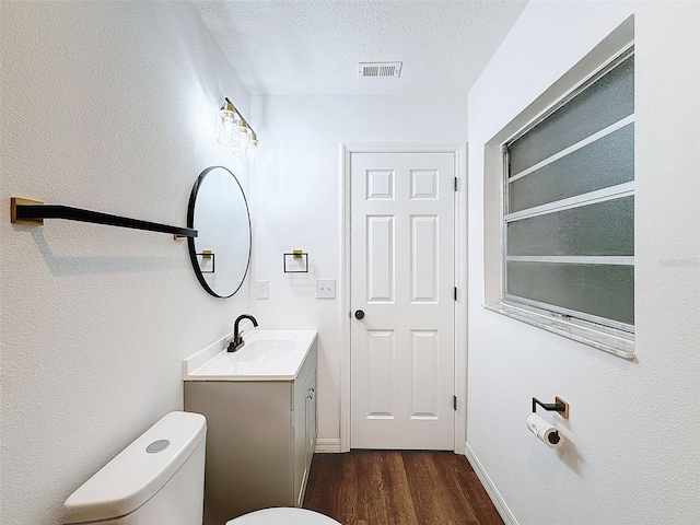 bathroom with vanity, toilet, a textured ceiling, and hardwood / wood-style floors