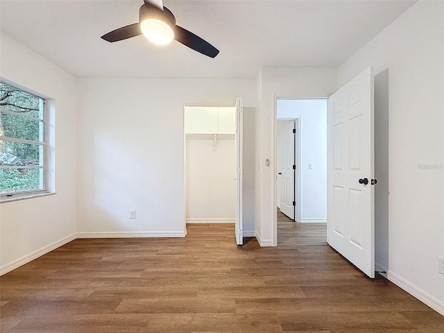 unfurnished bedroom with a closet, hardwood / wood-style floors, a walk in closet, and ceiling fan