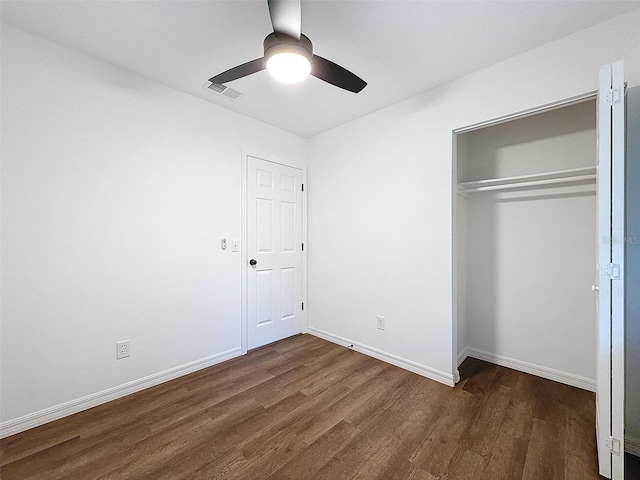 unfurnished bedroom with a closet, dark hardwood / wood-style floors, and ceiling fan