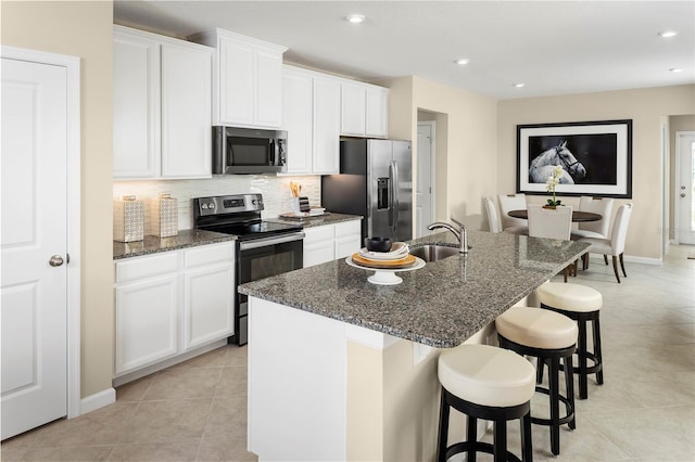 kitchen with white cabinetry, stainless steel appliances, and an island with sink