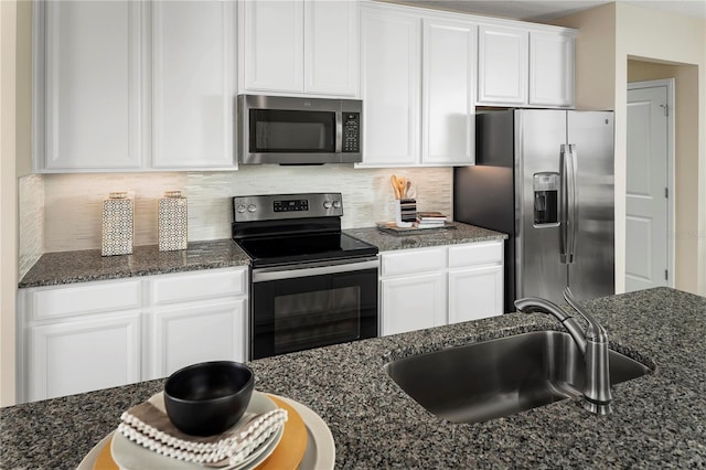 kitchen featuring sink, appliances with stainless steel finishes, white cabinetry, and dark stone counters