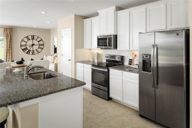 kitchen featuring white cabinets, dark stone countertops, stainless steel appliances, and sink