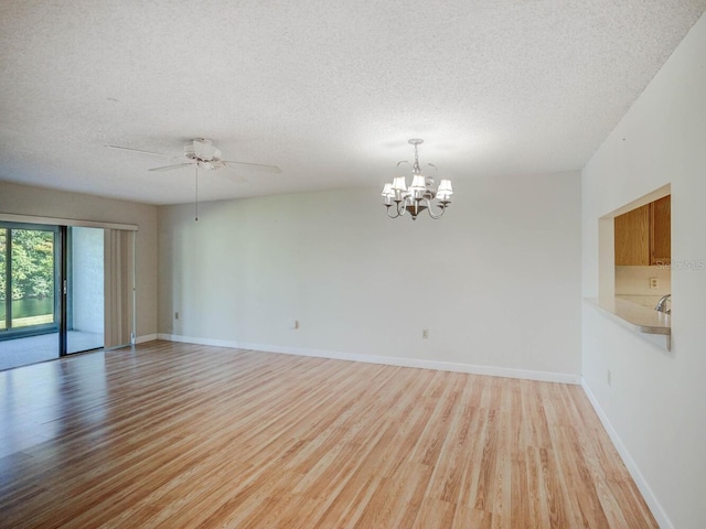 7719 Cosme Dr Unit 1, Hudson, FL 34667 - spare room featuring a textured ceiling, light wood finished floors, a ceiling fan, a chandelier, and baseboards