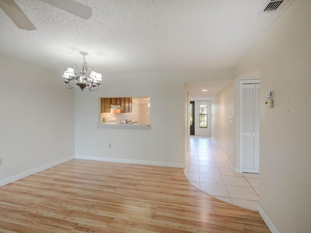 7719 Cosme Dr Unit 1, Hudson, FL 34667 - unfurnished room with light wood-style flooring, a chandelier, a textured ceiling, a ceiling fan, and baseboards