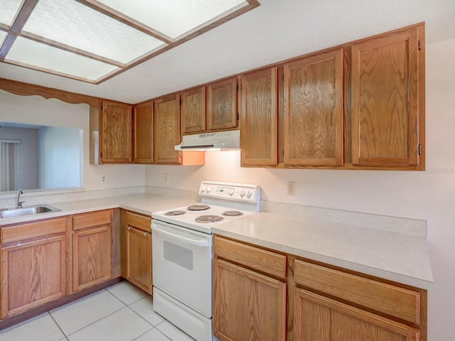 kitchen featuring under cabinet range hood, light countertops, white electric range oven, light tile patterned flooring, and a sink