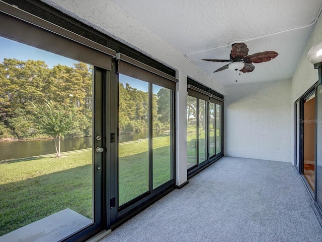 unfurnished sunroom with a water view and ceiling fan