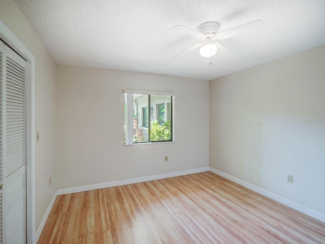 7719 Cosme Dr Unit 1, Hudson, FL 34667 - unfurnished bedroom featuring light wood-style flooring, a closet, a textured ceiling, baseboards, and a ceiling fan