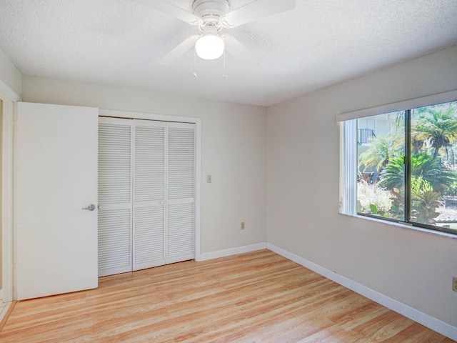 unfurnished bedroom featuring light wood finished floors, ceiling fan, baseboards, a closet, and a textured ceiling