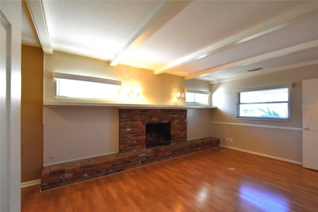 unfurnished living room featuring beam ceiling, hardwood / wood-style flooring, and a brick fireplace