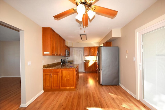 kitchen featuring light hardwood / wood-style floors, light stone countertops, kitchen peninsula, and appliances with stainless steel finishes