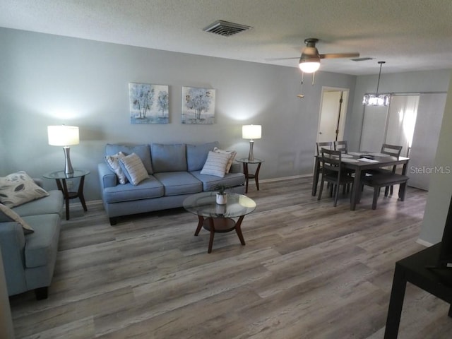 living room with ceiling fan, a textured ceiling, and hardwood / wood-style floors