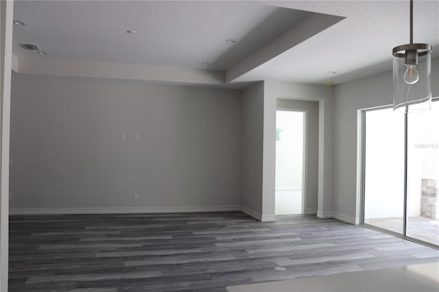 spare room featuring wood finished floors, plenty of natural light, visible vents, and baseboards