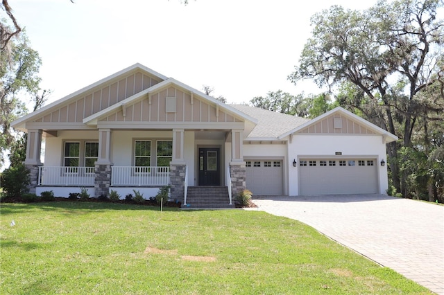 craftsman inspired home with board and batten siding, a porch, decorative driveway, a front yard, and an attached garage