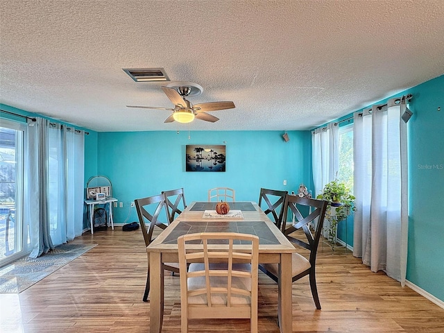 dining space featuring ceiling fan, a textured ceiling, and light wood-type flooring