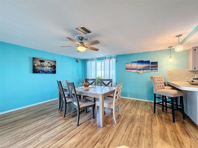 dining space featuring a textured ceiling, light hardwood / wood-style floors, and ceiling fan