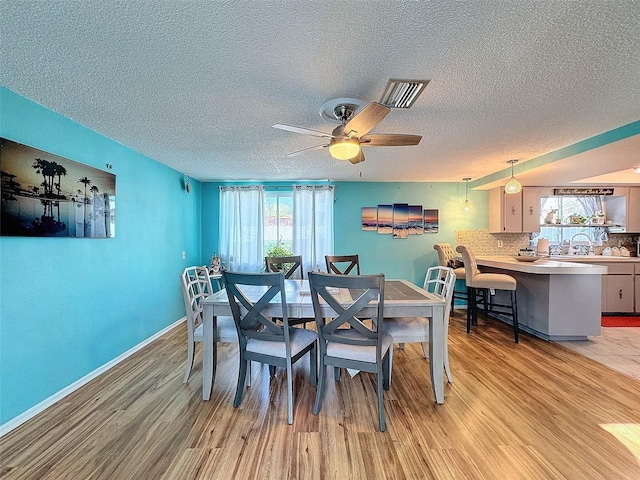 dining area featuring light hardwood / wood-style flooring, a textured ceiling, plenty of natural light, and ceiling fan