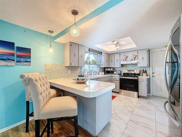 kitchen with kitchen peninsula, a kitchen bar, pendant lighting, gray cabinets, and appliances with stainless steel finishes