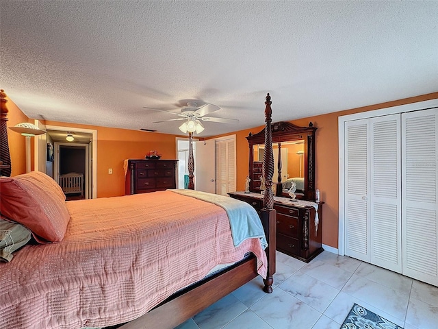 bedroom with ceiling fan, multiple closets, a textured ceiling, and light tile patterned floors