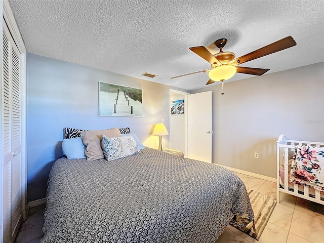 tiled bedroom with a closet, a textured ceiling, and ceiling fan