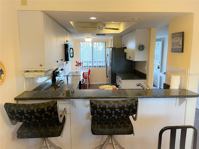 kitchen with white cabinetry, decorative backsplash, kitchen peninsula, and a kitchen bar