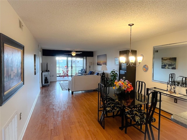 dining room with a textured ceiling, hardwood / wood-style flooring, and ceiling fan with notable chandelier