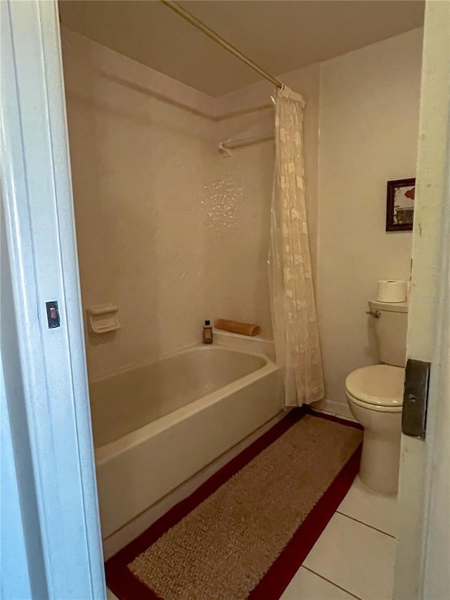 bathroom with tile patterned floors, shower / bath combo with shower curtain, and toilet