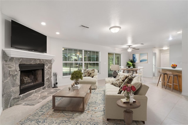 living room featuring a stone fireplace and ceiling fan