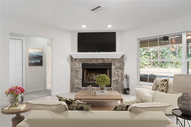 living room with a stone fireplace and carpet floors