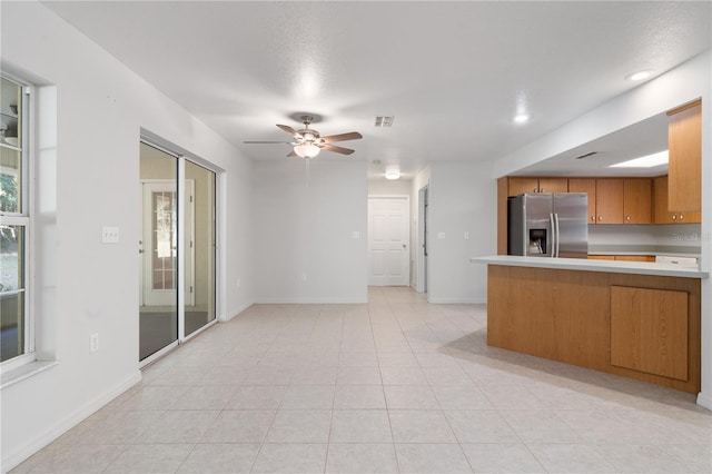 kitchen featuring stainless steel refrigerator with ice dispenser, ceiling fan, light tile patterned floors, and kitchen peninsula