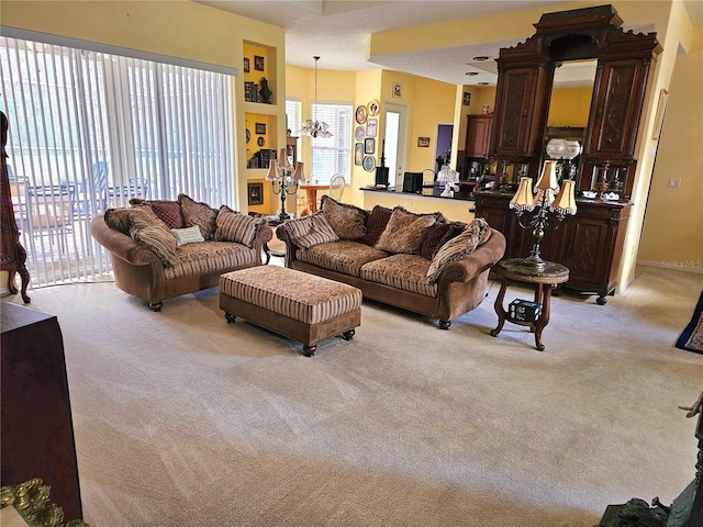 carpeted living room featuring an inviting chandelier