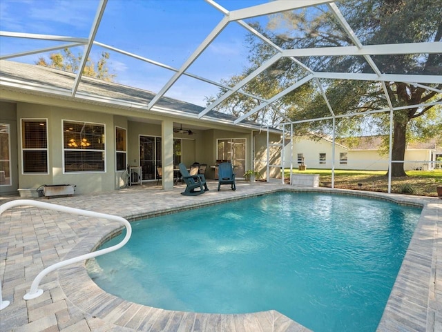 pool with glass enclosure, a patio area, and ceiling fan