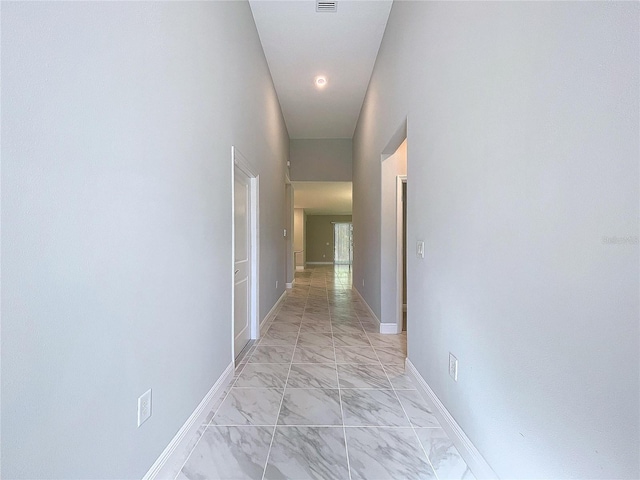 hallway with marble finish floor, visible vents, and baseboards