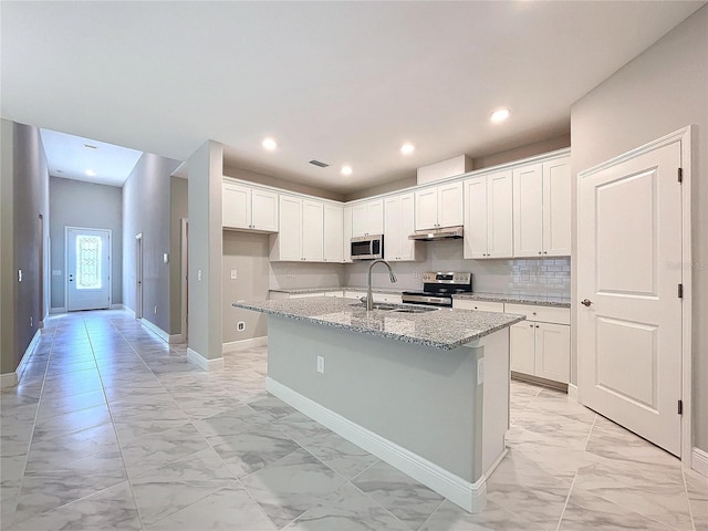 kitchen with light stone counters, marble finish floor, appliances with stainless steel finishes, a sink, and an island with sink